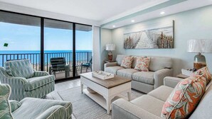 Un salon spacieux avec un balcon, un ensemble de canapés, une table basse et un tableau accroché au mur.