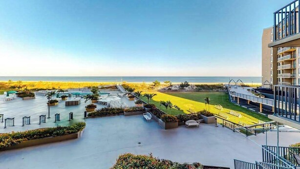 Een hotel met een dakterras, uitzicht op het strand en een aangelegde tuin met zitplaatsen.