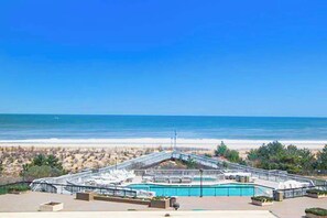 A pool area with a bridge, a beach view, and a clear sky. - Sea Colony Ocean 3rd floor condo w/ free WiFi, shared sauna, and pool (Bethany Beach)