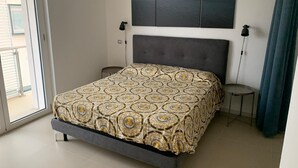 Una camera da letto con un letto, una testiera, un comodino, una lampada e vista sull'esterno.