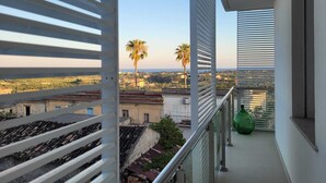 Un balcone con vista sulla città, tra cui palme e edifici.