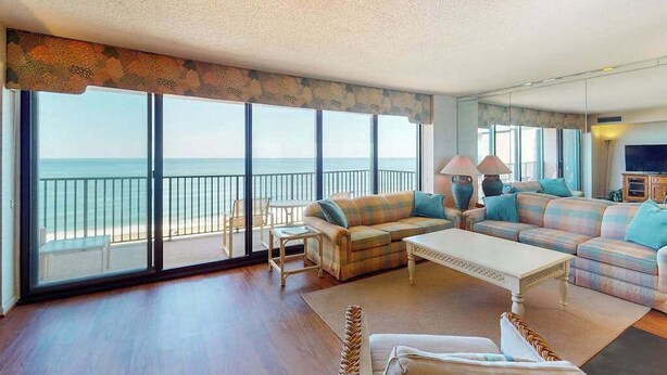 A spacious living room with a large sliding glass door leading to a balcony overlooking the ocean. - Sea Colony oceanfront 15th-floor condo with pool & tennis/basketball courts (Bethany Beach)