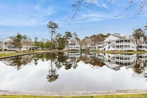 A waterfront hotel with multiple buildings, a reflecting pool, and surrounding trees. - Sea Colony Tennis 1st floor condo w/ gym, basketball court, and shared sauna (Bethany Beach)