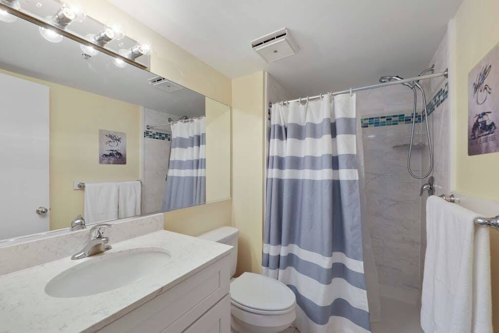 Ein Badezimmer mit Waschbecken, Spiegel, Dusche und Toilette.