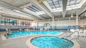 Una piscina interior con hidromasaje, sillones reclinables y un amplio ventanal.