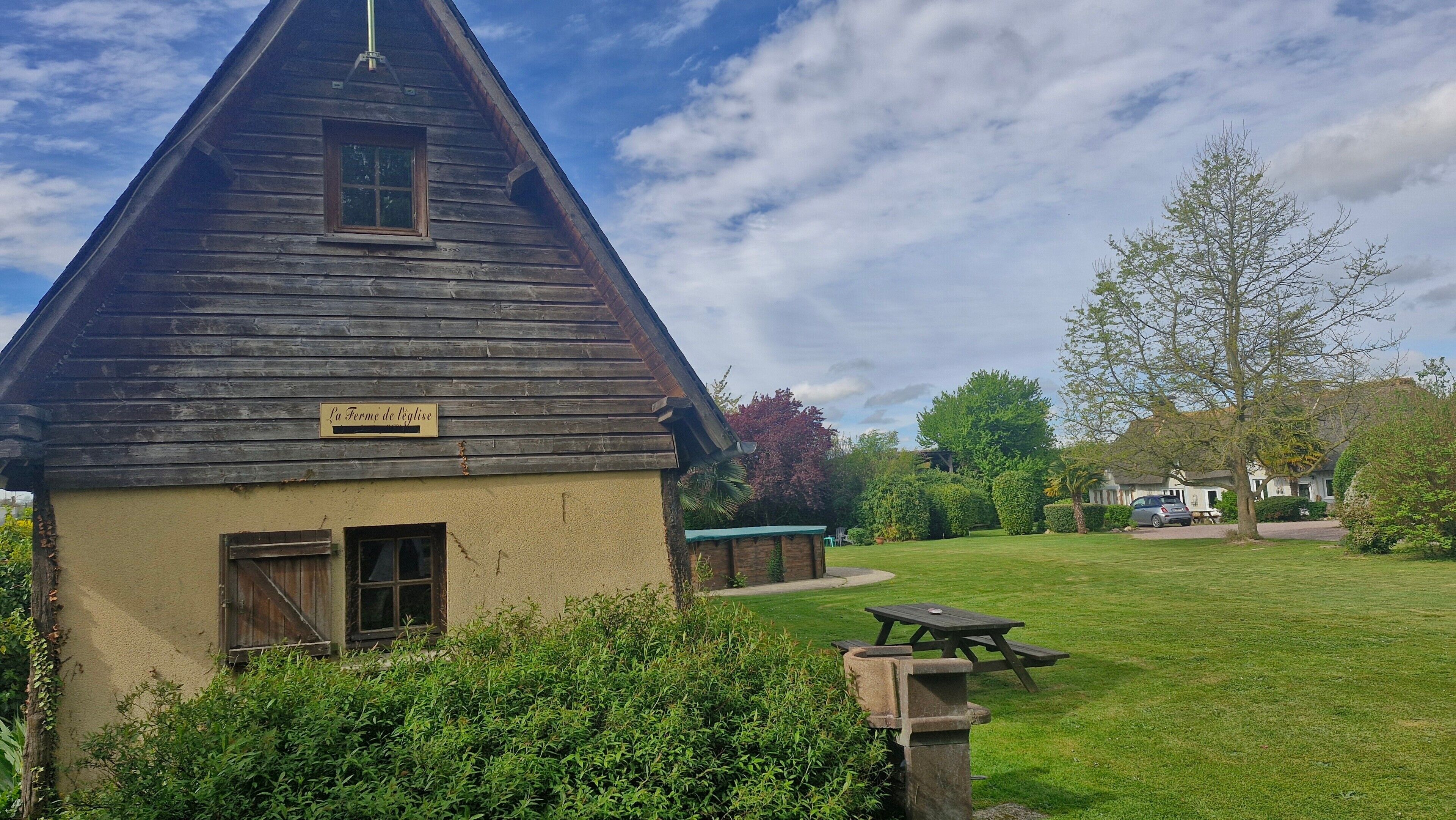 En rustik träbyggnad med en skylt där det står ”La Ferme de legnise”.