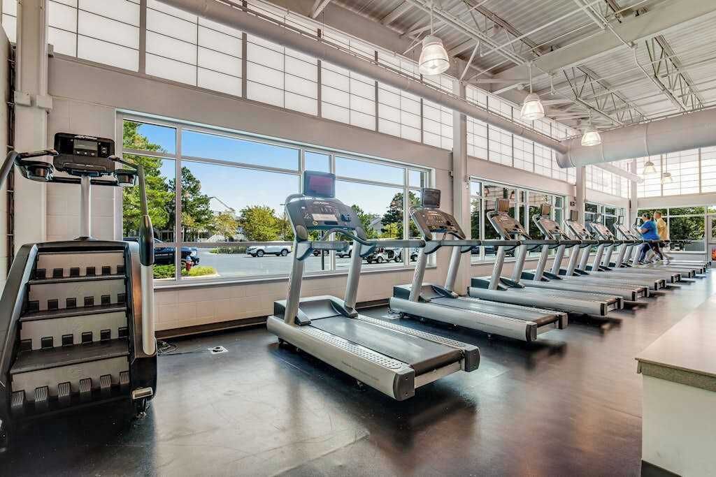 A gym with treadmills, a stair climber, and a large window with a view of the outside.