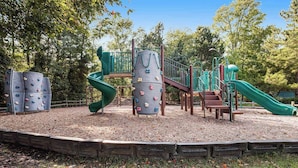 Une aire de jeux avec des structures d’escalade, des toboggans et un banc en bois.