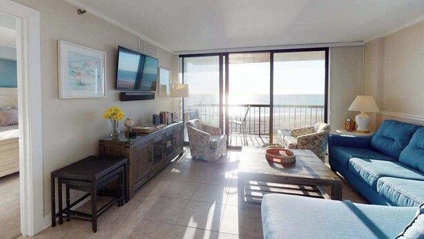 A living room with a sofa, a TV, a balcony with a view, and a dining area. - Sea Colony Ocean 5th floor condo w/ balcony, shared sauna, and pool (Bethany Beach)