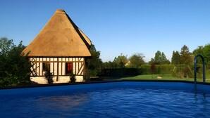 Un edificio con techo de paja y una piscina delantera.