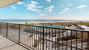 Een balkon met uitzicht op een strand en een zwembad.