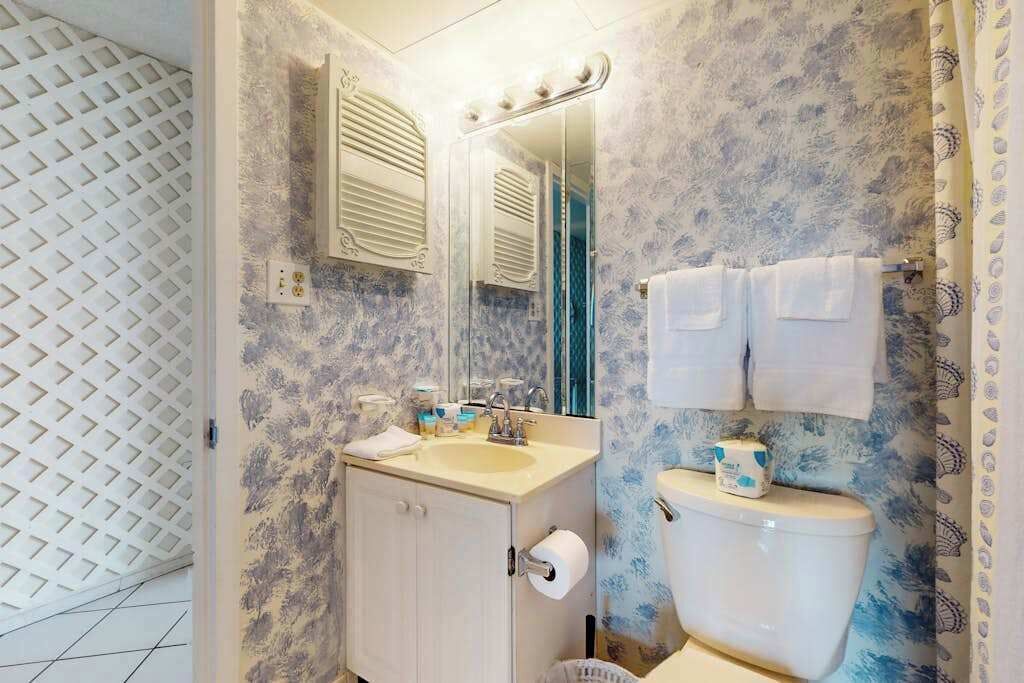Ein Badezimmer mit Waschbecken, Spiegel, Toilette und Wandverkleidung mit Muster.