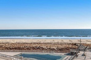 Vista de la playa con una zona arenosa, una sección cercada y una construcción con techo.