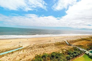 A beach view with a pathway leading to a building. - Sea Colony Ocean 8th floor condo w/ gym, tennis court, and balcony (Bethany Beach)