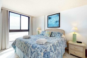A bedroom with a large bed, a window, a framed artwork, and a nightstand with a lamp. - Sea Colony Ocean 8th floor condo w/ gym, tennis court, and balcony (Bethany Beach)