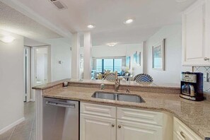 A modern kitchen with a dishwasher, double sink, and a coffee maker. - Sea Colony Ocean 9th floor condo with elevator, gym, and pool (Bethany Beach)