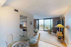 Ein Wohnzimmer mit Essbereich, ein Balkon mit Aussicht und eine Küche im Hintergrund.
