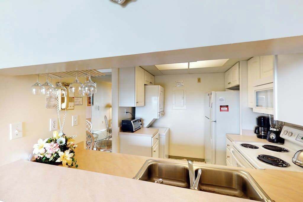 A modern kitchen with white cabinets, a stainless steel sink, a microwave, a stove, and a toaster.