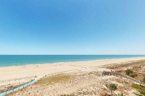 Ein Strand mit klarem Himmel, sandigem Ufer und einer Holzpromenade.