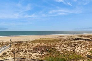 A beach view with a wooden boardwalk, sandy dunes, and the ocean. - Sea Colony Ocean 4th floor condo with gym, sauna, & balcony (Bethany Beach)