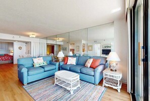 A living room with two blue sofas, a white coffee table, and a small white side table with a lamp. - Sea Colony Ocean 4th floor condo with gym, sauna, & balcony (Bethany Beach)