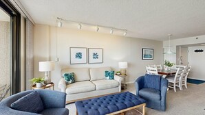 A modern living room with a sofa, two armchairs, a coffee table, and a dining area with a table and chairs. - Sea Colony Ocean 7th floor condo w/ basketball court, pool, and elevator (Bethany Beach)