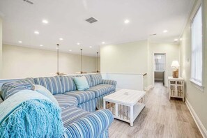 Una sala de estar moderna con un sofá a rayas, una mesa de centro blanca y una mesita auxiliar.