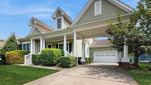 Ein Wohnhaus mit überdachter Veranda, Garage und gepflegtem Rasen.