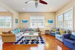 A spacious living room with a sofa, armchairs, a coffee table, and artwork on the walls. - Bayside Resort house with pool, lakefront, golf on-site, & tennis court (Selbyville)