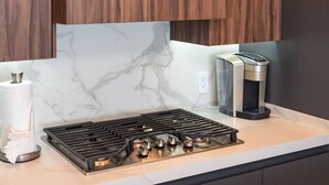 A kitchen with a gas stove, a coffee maker, and a marble backsplash. - Beachfront 2BR Condo Pool Ocean Views Resort (Puerto Peñasco)