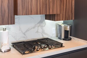A kitchen with a gas stove, a coffee maker, and a marble backsplash. - Beachfront 2BR Condo Pool Ocean Views Resort (Puerto Peñasco)