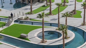 A pool area with palm trees, a circular water feature, and a staircase leading to a building. - Beachfront 2BR Condo Pool Ocean Views Resort (Puerto Peñasco)