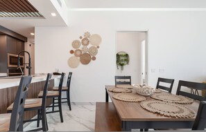 Una cucina moderna con forno integrato, un'area pranzo con tavolo e sedie in legno e un elemento decorativo a parete.