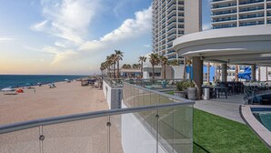 A beachfront hotel with a pool, palm trees, and a beach. - Beachfront 2BR Condo Pool Ocean Views Resort (Puerto Peñasco)