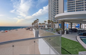 A beachfront hotel with a pool, palm trees, and a beach. - Beachfront 2BR Condo Pool Ocean Views Resort (Puerto Peñasco)
