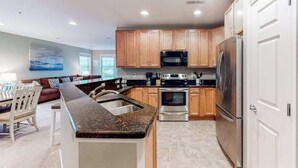 A modern kitchen with granite countertops, stainless steel appliances, and wooden cabinets. - Bayside Resort 4th floor condo w/ gym, tennis court, and free WiFi (Selbyville)