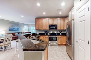 A modern kitchen with granite countertops, stainless steel appliances, and wooden cabinets. - Bayside Resort 4th floor condo w/ gym, tennis court, and free WiFi (Selbyville)