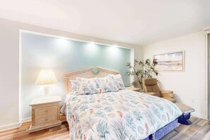 A bedroom with a bed, nightstand, lamp, chair, and a painting on the wall. - Sea Colony Ocean 8th floor condo w/ shared sauna, pool, and balcony (Bethany Beach)