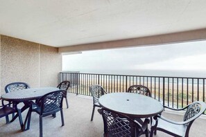 A balcony with a table and chairs, overlooking a beach. - Sea Colony Ocean 8th floor condo w/ shared sauna, pool, and balcony (Bethany Beach)