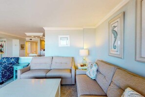 A living room with two sofas, a coffee table, a lamp, and framed artwork on the wall. - Sea Colony Ocean 4th floor condo w/ gym, elevator, and tennis court (Bethany Beach)