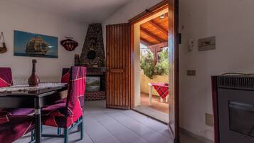 A room with a fireplace, a dining table with chairs, a television, and a door leading outside.