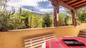 A covered outdoor seating area with a bench and a table with a tray.