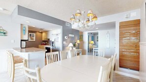 Une cuisine moderne avec un îlot central, une table à manger blanche et des chaises.
