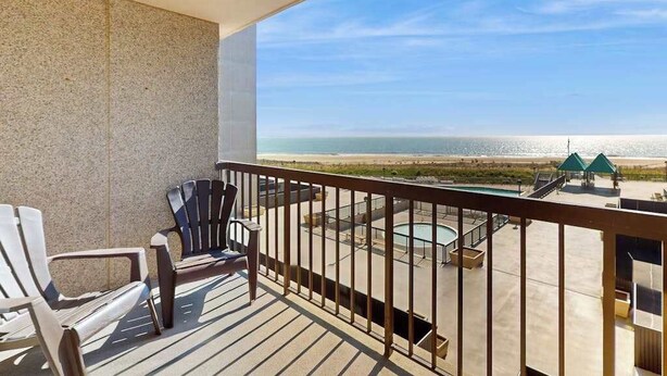 Un balcon avec vue sur la plage, une piscine et un espace salon extérieur.