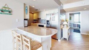 Une cuisine moderne dotée d’un îlot central, de meubles blancs et d’un réfrigérateur.