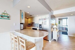 A modern kitchen with a central island, white cabinetry, and a refrigerator. - Sea Colony Ocean updated 3rd-floor condo with pool & tennis court (Bethany Beach)