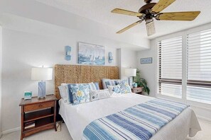 A bedroom with a bed, a nightstand, a wall-mounted lamp, a ceiling fan, and a window with blinds. - 1st-floor Sea Colony Ocean condo with gym, sauna, & pool (Bethany Beach)