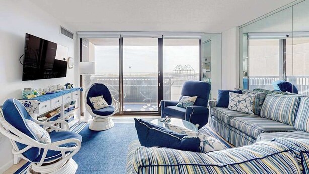 Uma sala de estar moderna com sofá, poltronas, televisão de tela plana e varanda com vista.