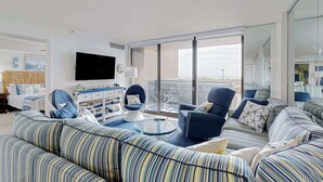 Uma sala de estar moderna com sofás listrados, uma mesa de centro de vidro e uma televisão de tela plana.