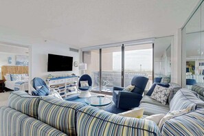 Ein modernes Wohnzimmer mit gestreiften Sofas, einem Glastisch und einem Flachbildfernseher.